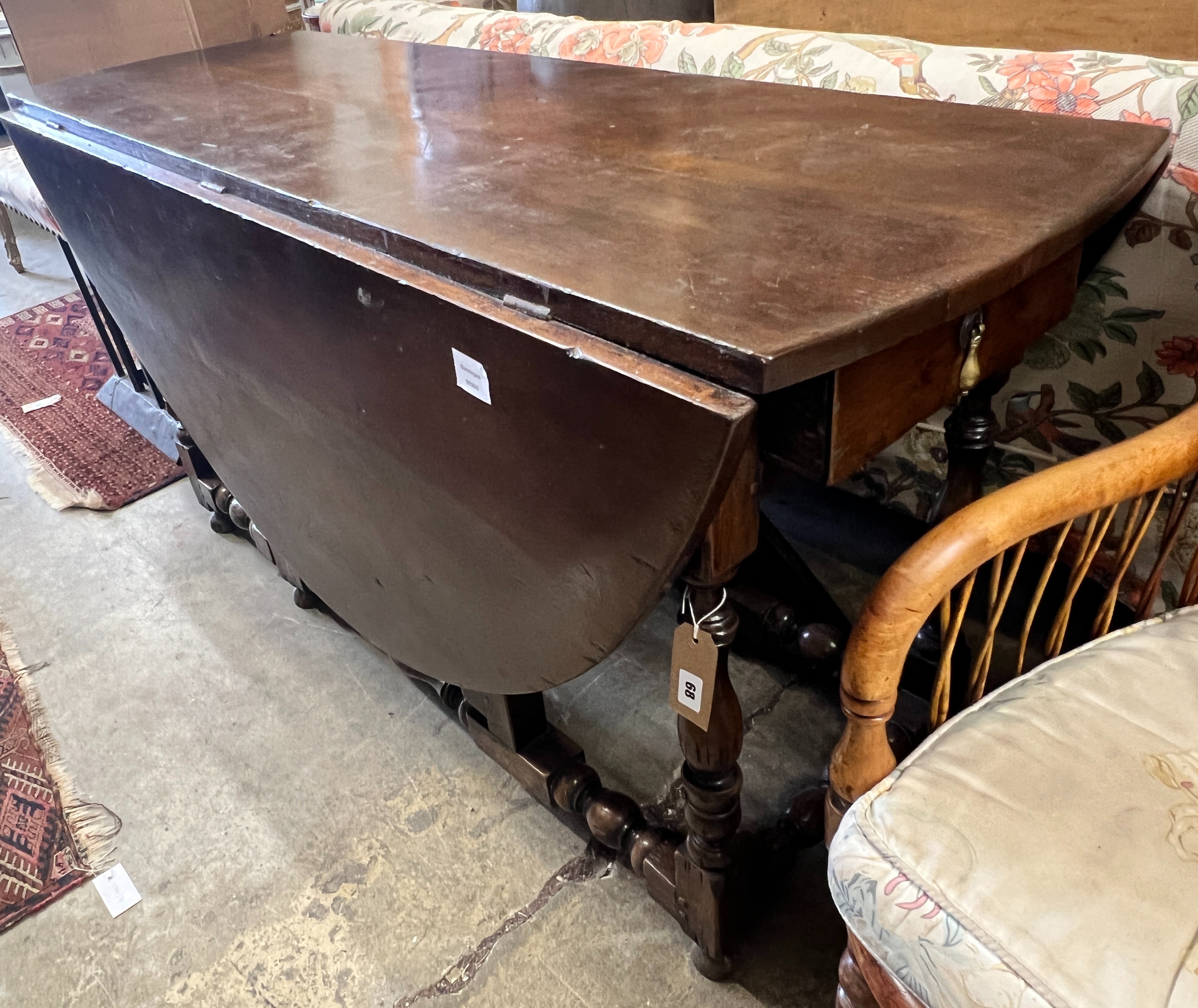 An early 18th century style oak oval topped gateleg dining table, (one leaf in need of repair), length 140cm, width 52cm, height 75cm